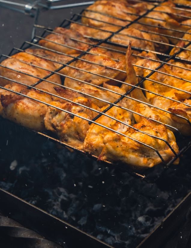 BBQ picnic time Roasted chicken legs and wings on grill. Grilling meat on outdoor grill grid tasty barbeque chicken steak with smoke flames juicy meat in the backyard in summer