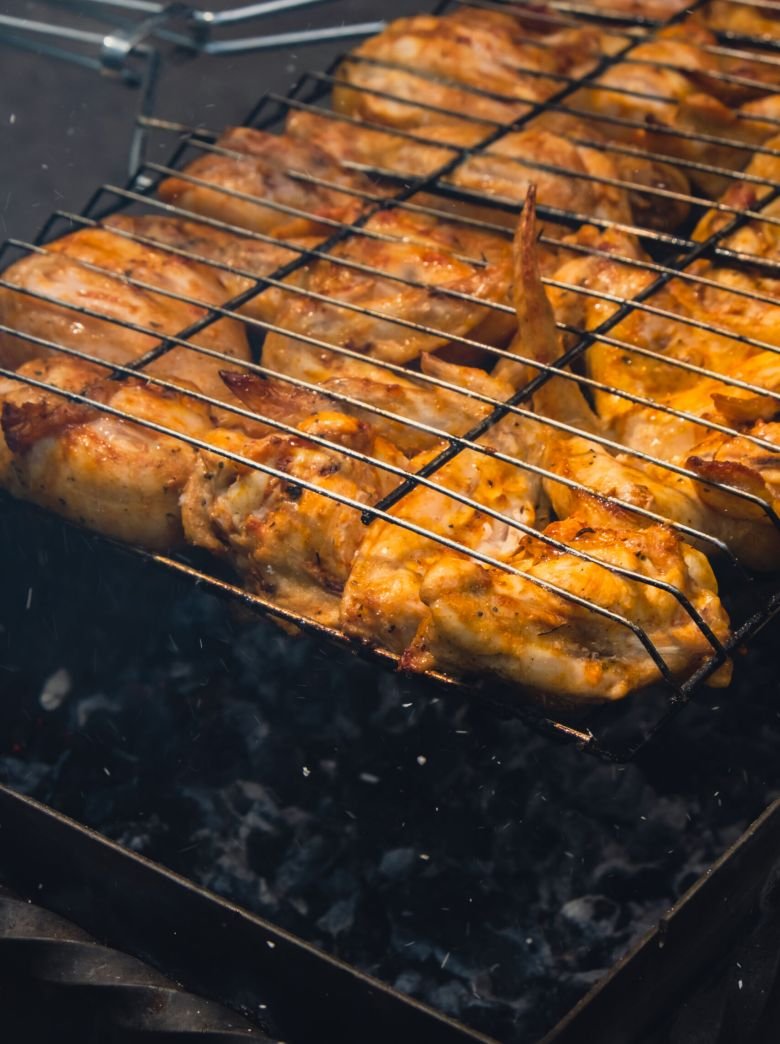 BBQ picnic time Roasted chicken legs and wings on grill. Grilling meat on outdoor grill grid tasty barbeque chicken steak with smoke flames juicy meat in the backyard in summer